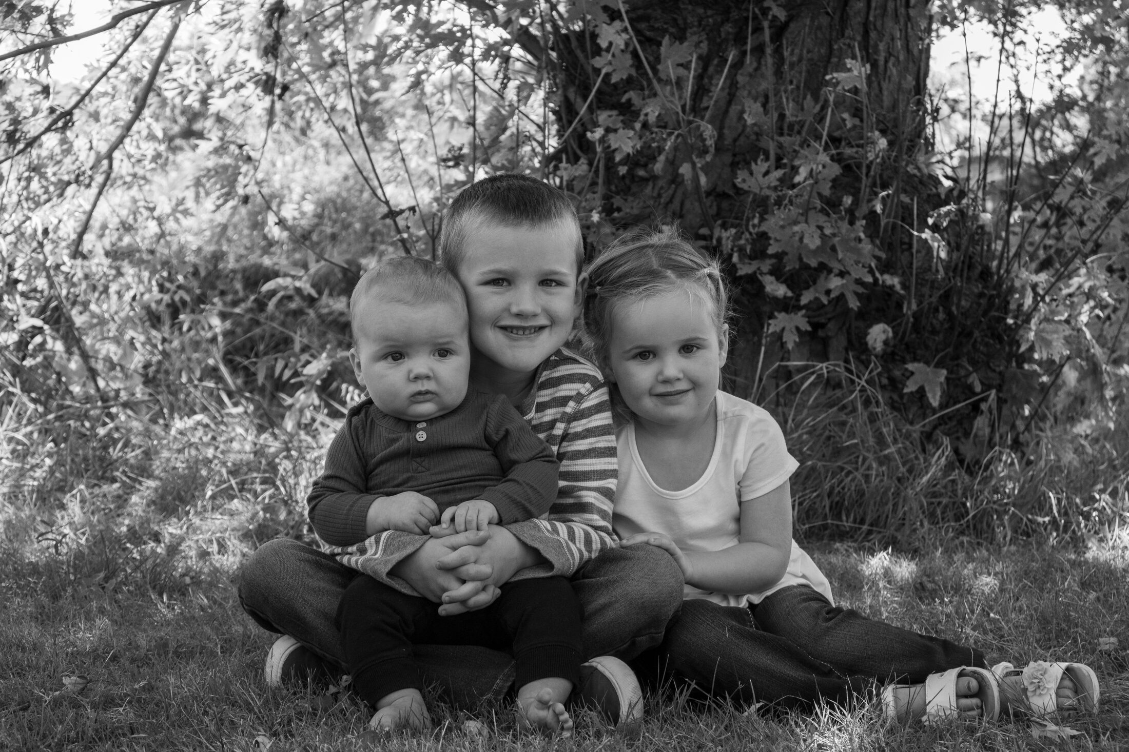 Three children sitting together in black and white